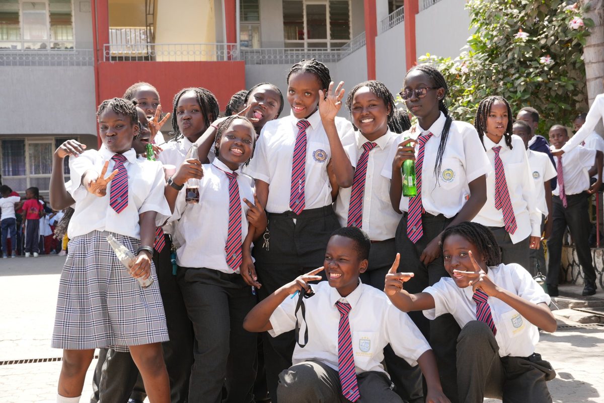 Junior Secondary pupils in white shirts and striped ties laughing in the courtyard