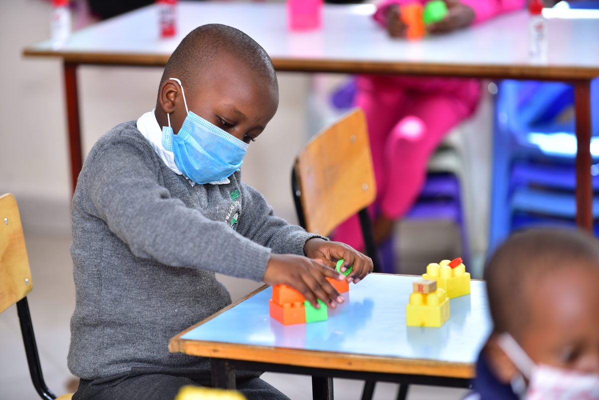A boy in a grey jumper fitting two building blocks together