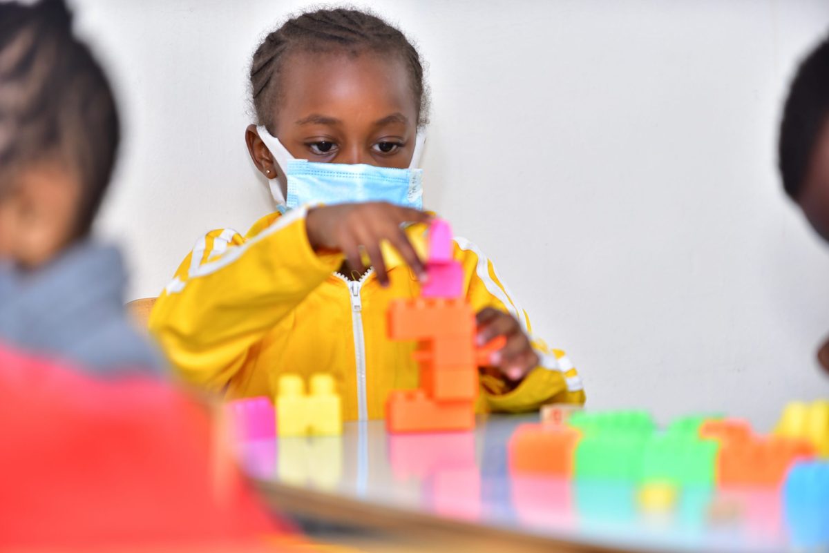 A girl in a yellow tracksuit building with bright blocks