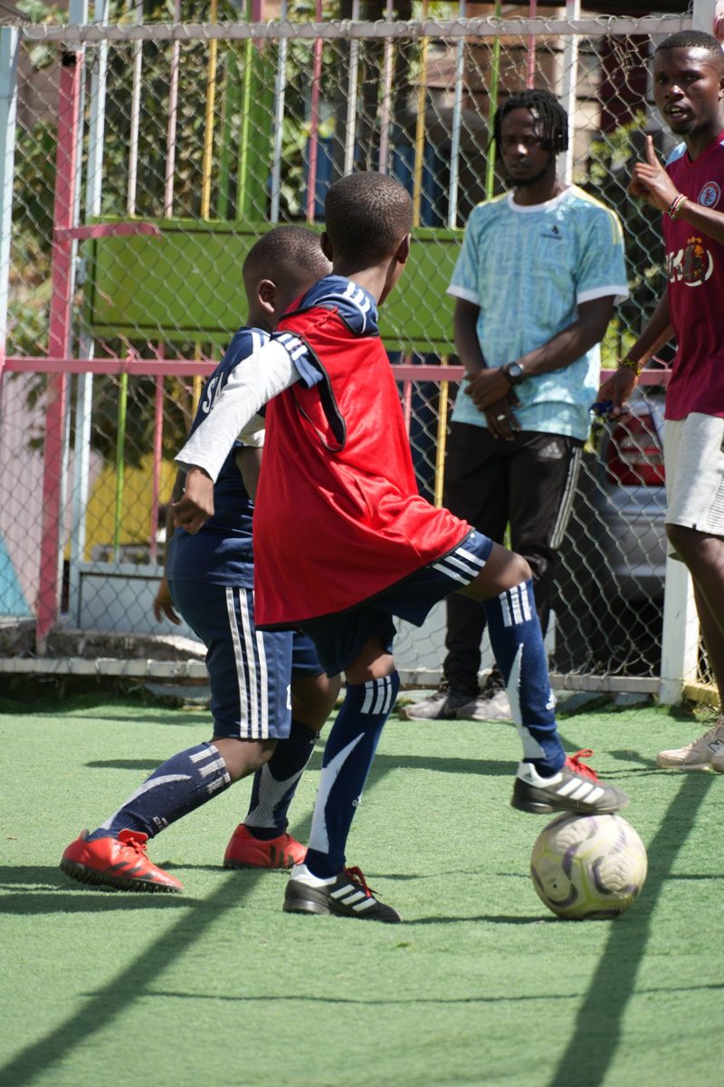 Primary pupils chasing a football on the turf pitch