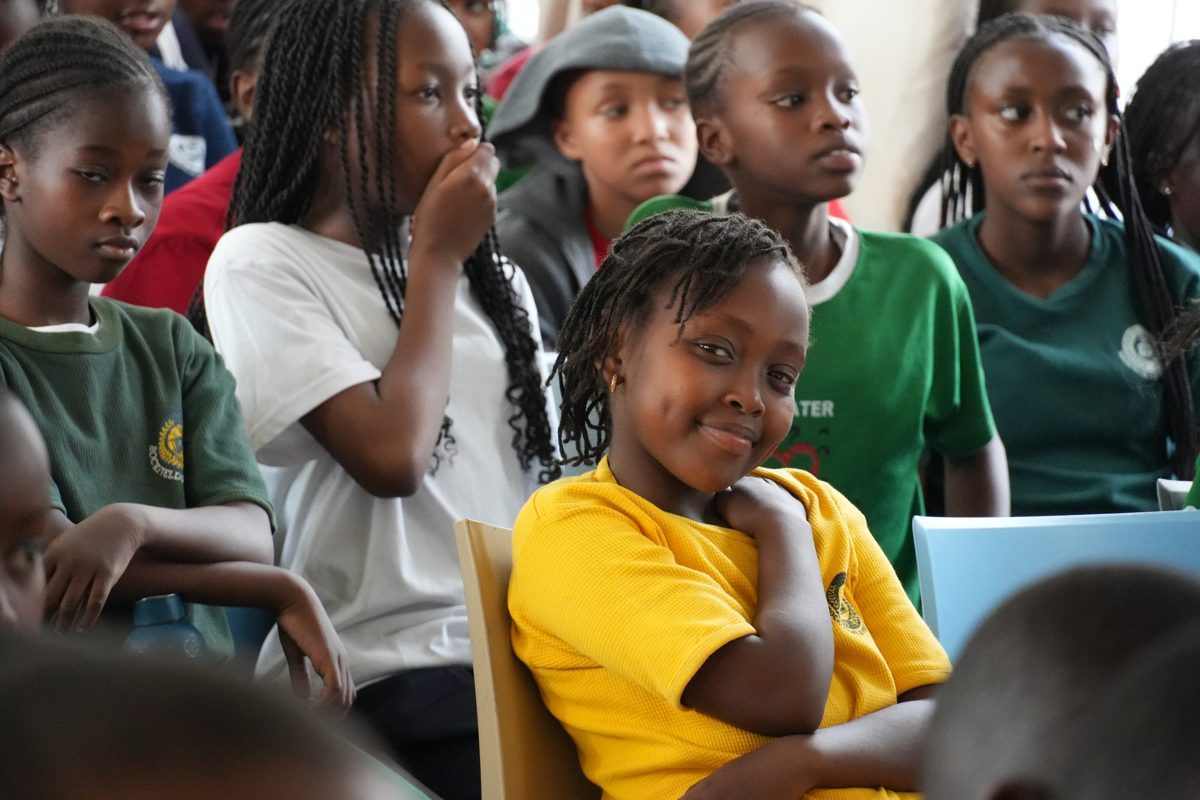Primary pupils in bright T-shirts smiling during an assembly in the hall