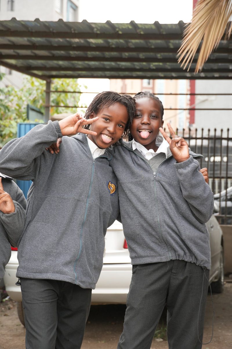 Two primary girls in grey school fleeces smiling together